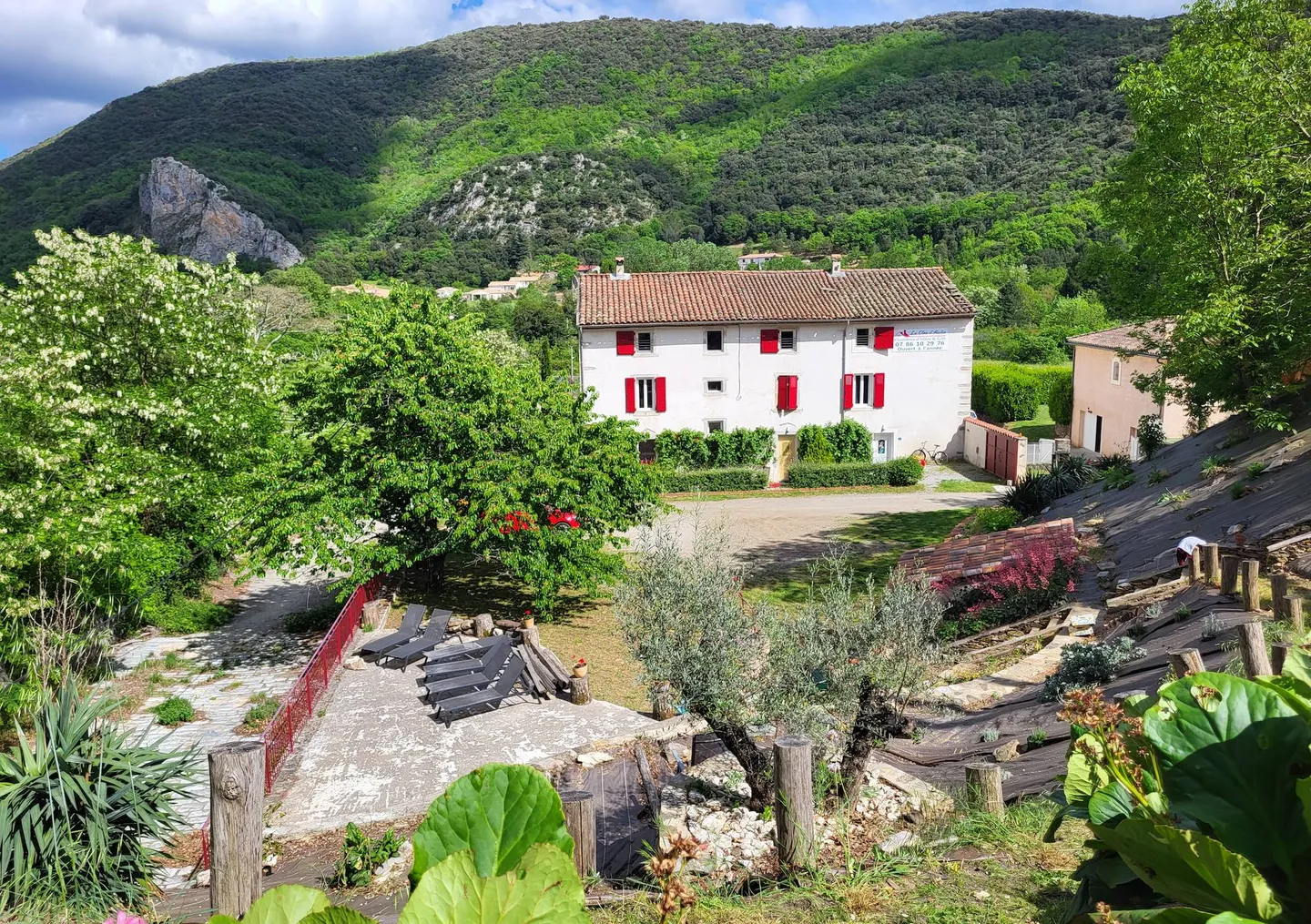 Plan aérien du Clos d'Audio, avec la maison en premier plan, et la montagne derrière.